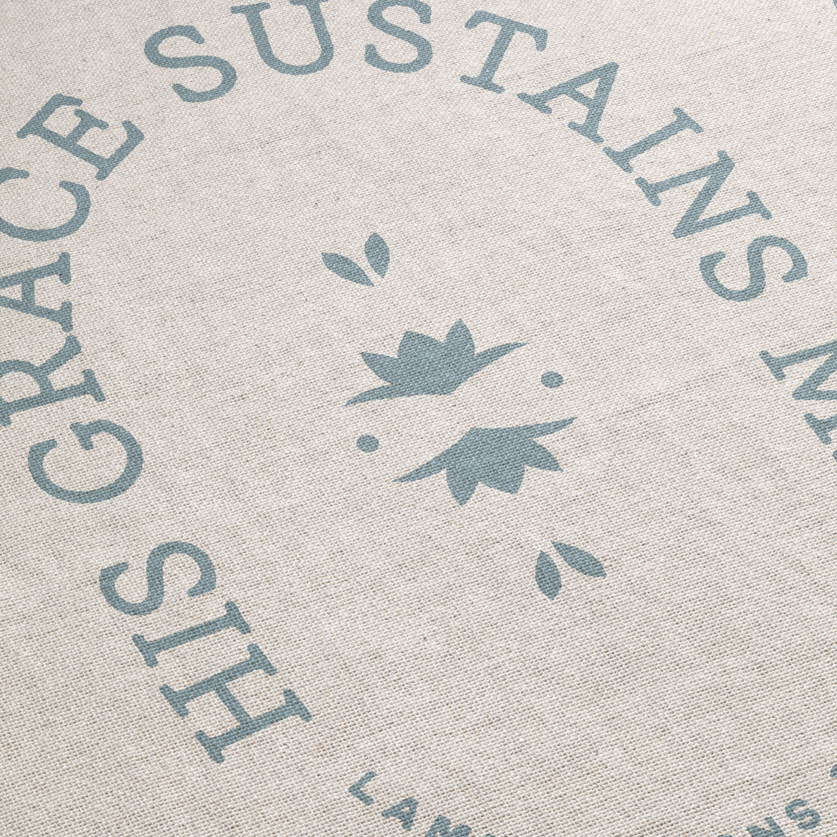 Textured fabric with 'His Grace Sustains My Land' printed in blue on a beige background