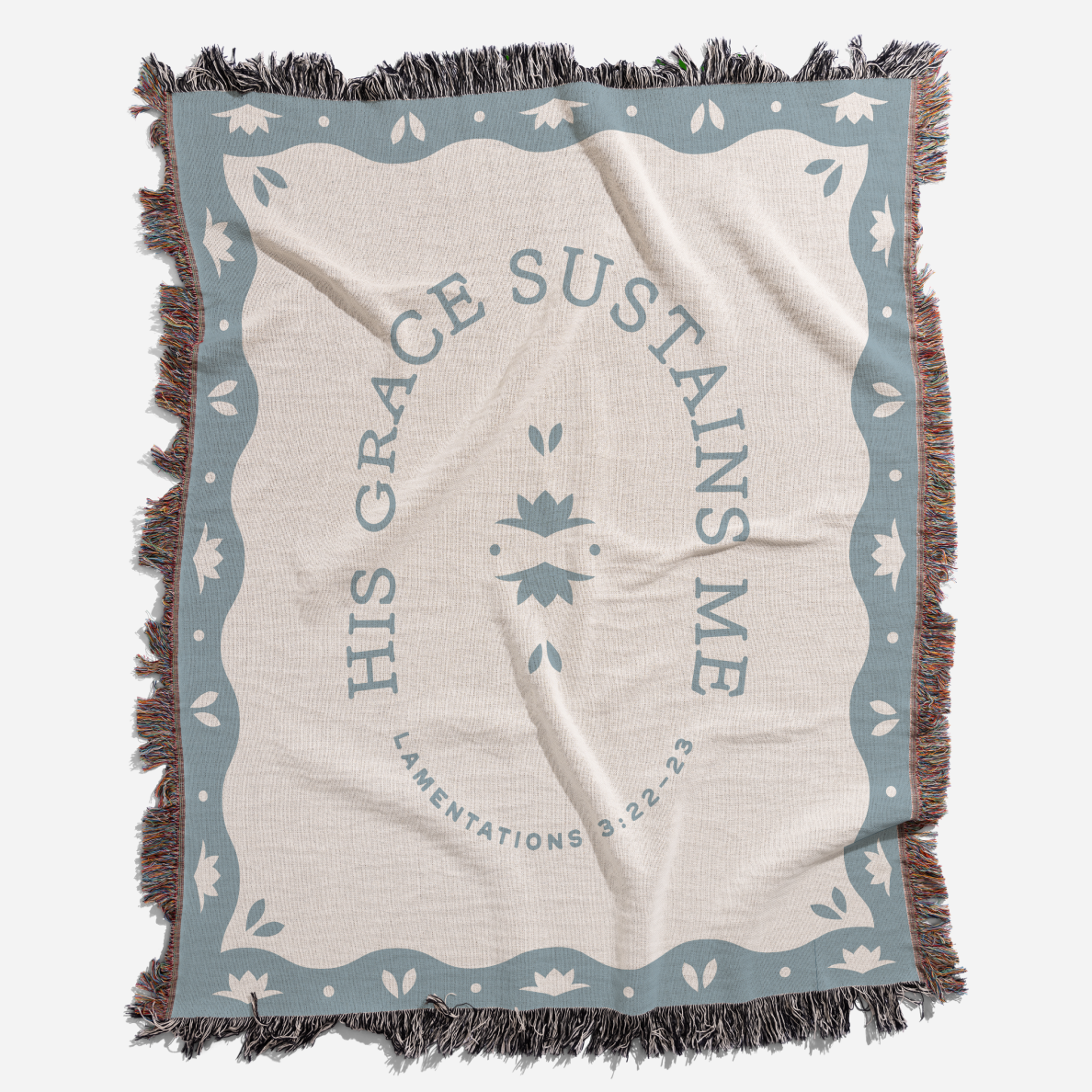 Blanket with 'His Grace Sustains Me' text and decorative border on a white background