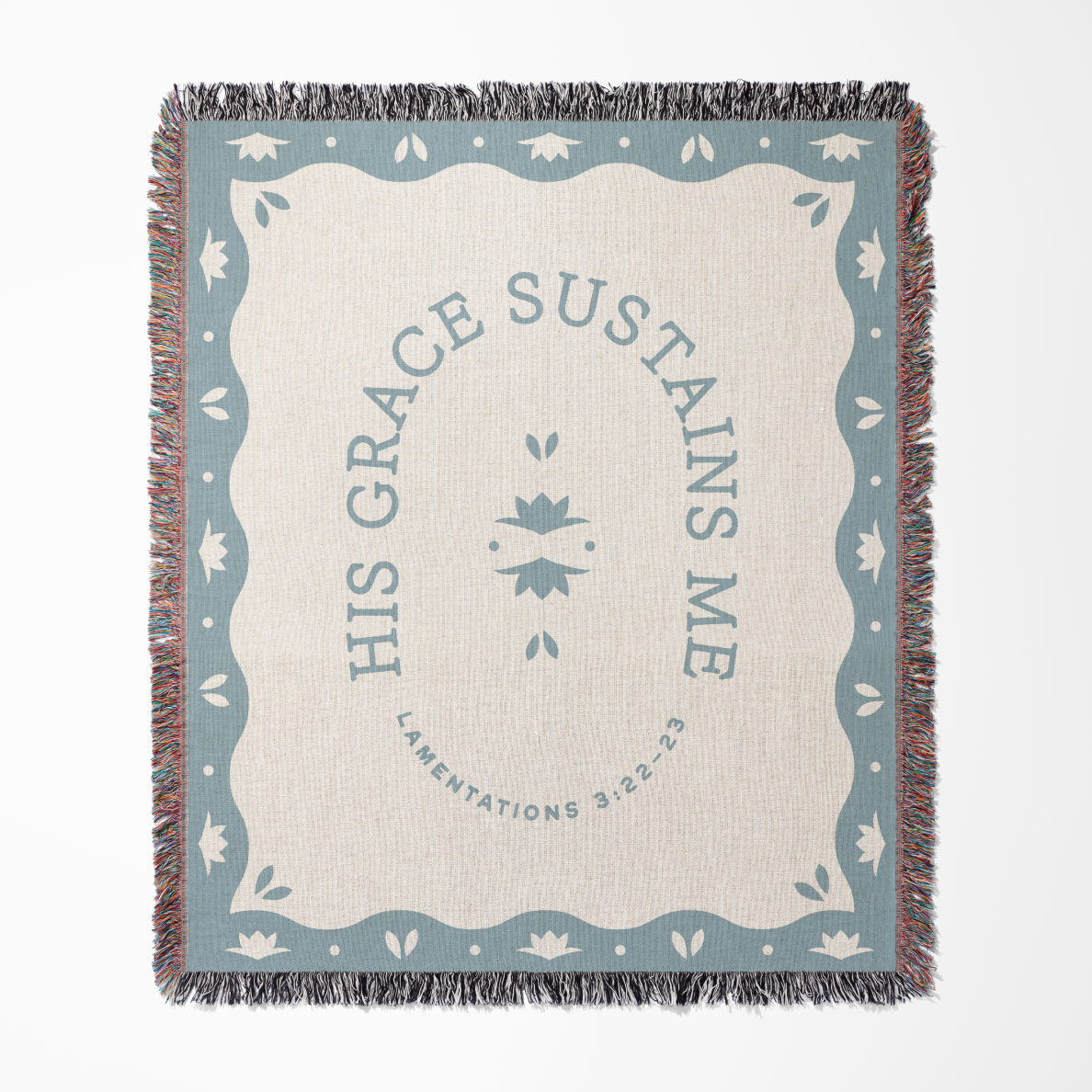 Blanket with 'His Grace Sustains Me' text and decorative border on a white background