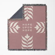 Blanket with floral patterns and 'Hope Upon Hope' text on a pink background