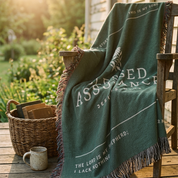 Green blanket with text draped over a chair outdoors on a wooden deck.