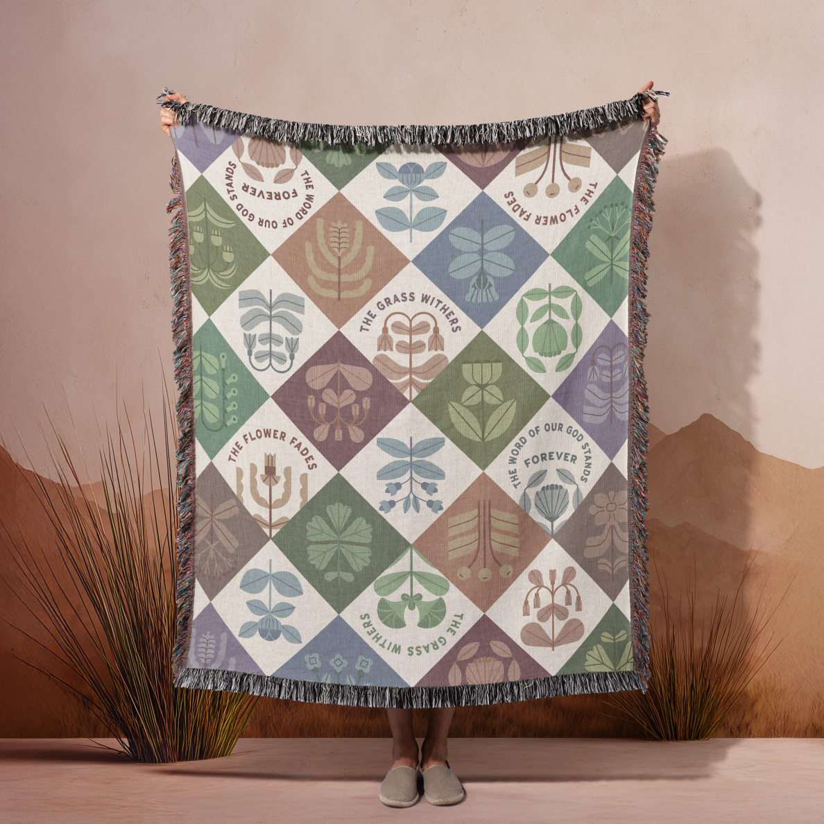 Person holding a patterned blanket with geometric design against a neutral background
