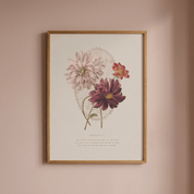 A framed botanical art print featuring three dahlia flowers in soft pink, burgundy, and coral tones, hanging on a dusty pink wall.