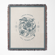 Blanket with floral design and text 'Jesus makes all things new' on a beige background