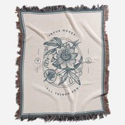 Blanket with floral design and text 'Jesus makes all things new' on a white background