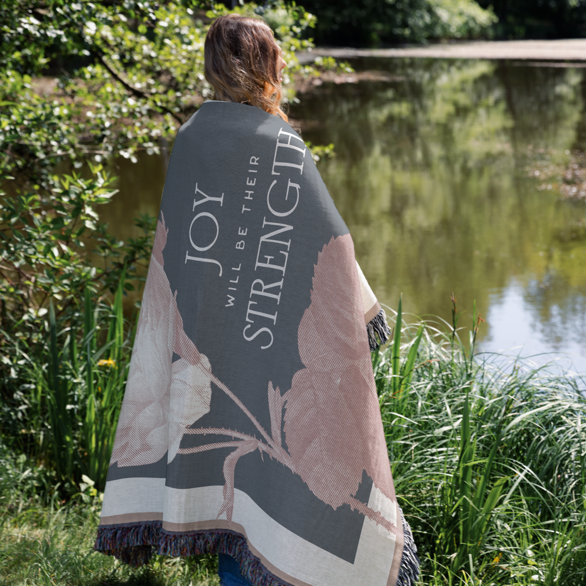 Person wrapped in a blanket with motivational text by a pond