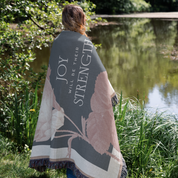 Person wrapped in a blanket with motivational text by a pond