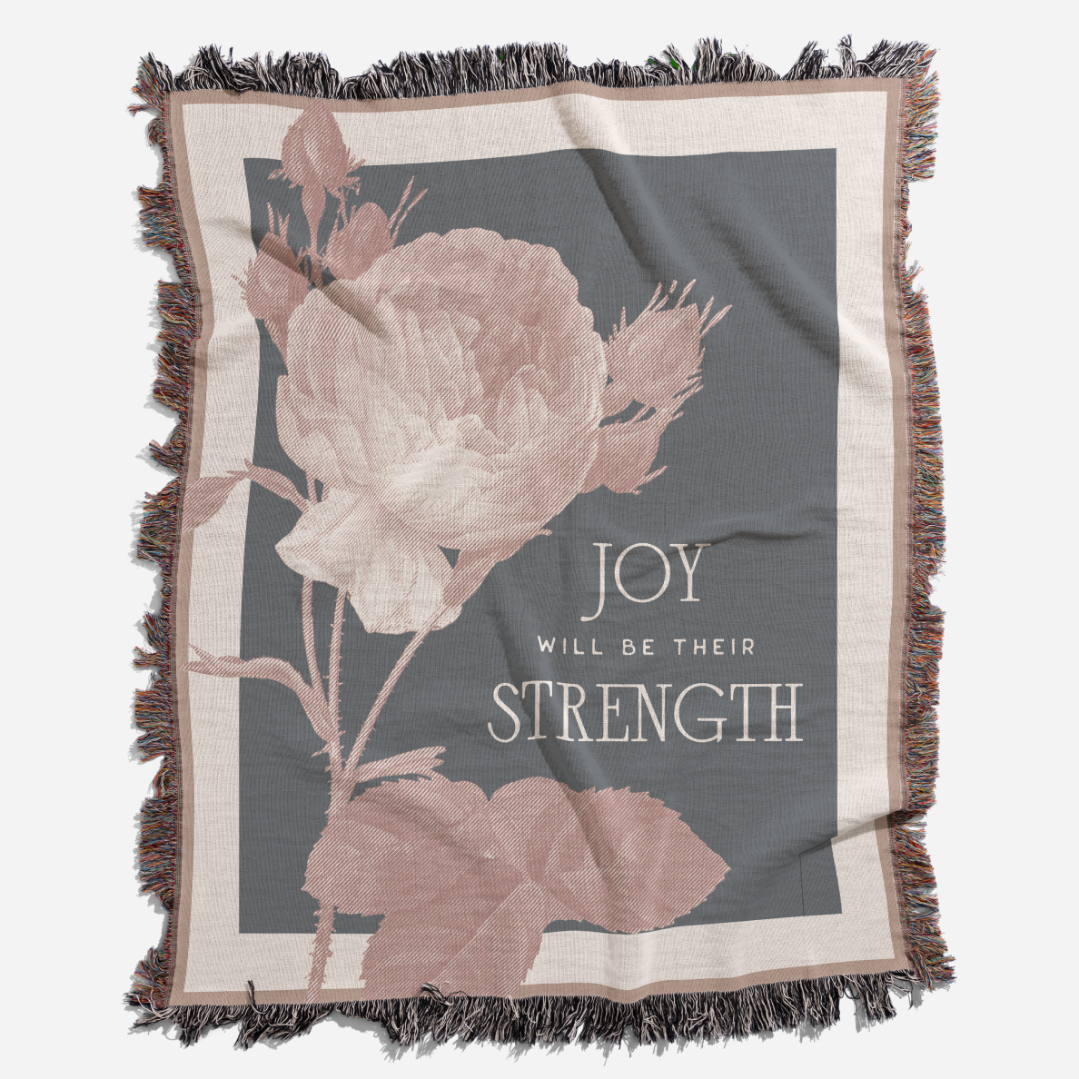Blanket with floral design and text 'Joy will be their strength' on a gray background