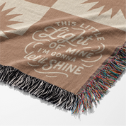 Neutral-toned woven blanket with suns and the phrase “This little light of mine, I’m gonna let it shine,” made from 100% cotton with fringe; perfect for nurseries or Christian baby gifts.