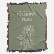 Green throw blanket with floral design and text on a white background