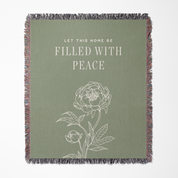 Green throw blanket with floral design and text 'Let this home be filled with peace' on a white background