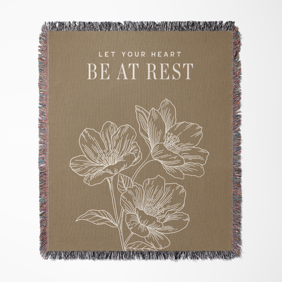 Blanket with floral design and text 'Let your heart be at rest' on a beige background