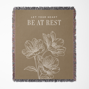 Blanket with floral design and text 'Let your heart be at rest' on a beige background