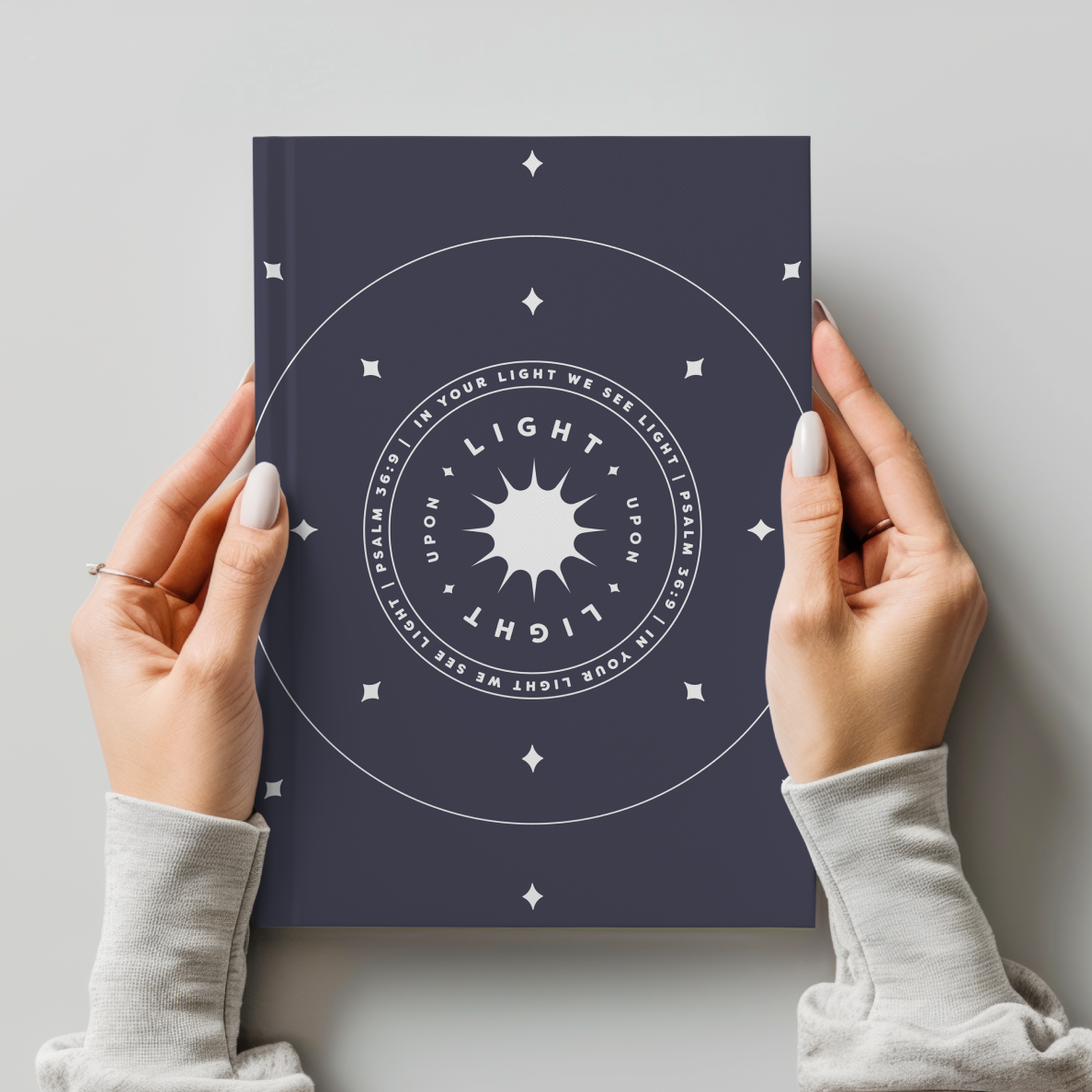 Person holding a book with a circular design and text on a light gray background