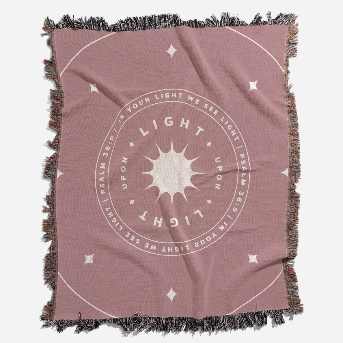 Pink throw blanket with 'Light Upon Light' design and fringed edges on a white background