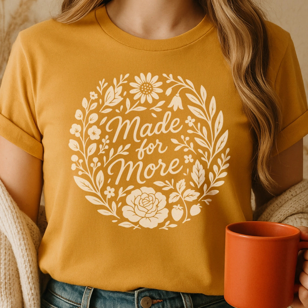 Christian t-shirt with “Made for More” in handwritten script surrounded by flowers and plants; soft cotton unisex tee symbolizing faith, growth, and divine purpose.