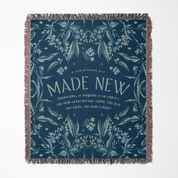 Navy blue woven blanket with floral patterns and 'MADE NEW' text on a white background