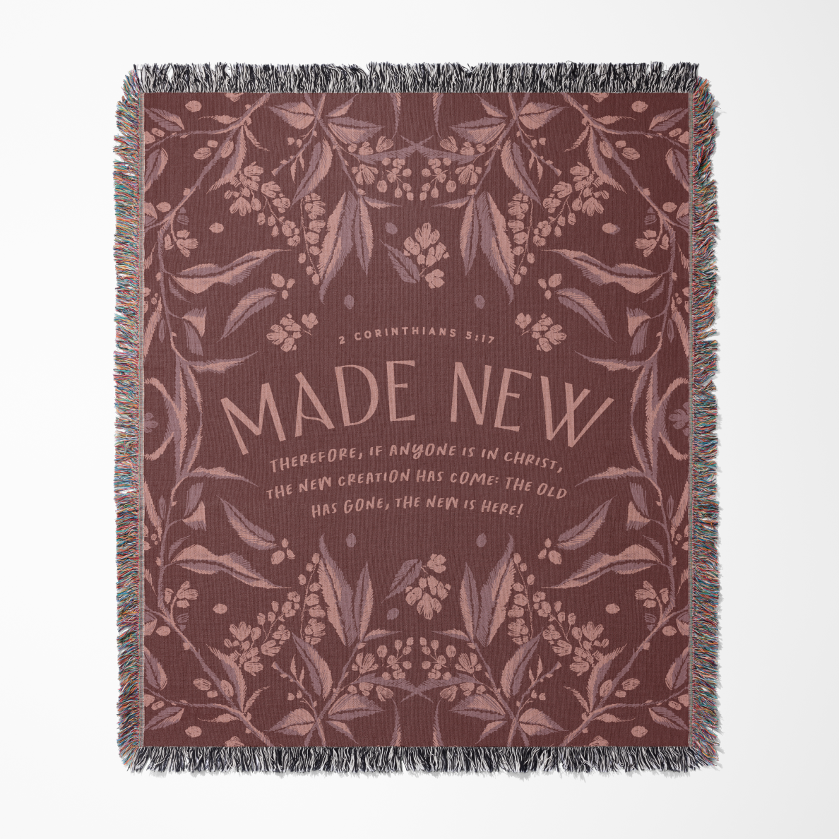 Decorative throw blanket with floral pattern and 'Made New' text on a white background
