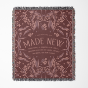 Decorative throw blanket with floral pattern and 'Made New' text on a white background