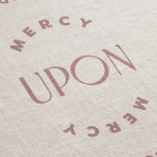 Text 'MERCY UPON MERCY' printed on a textured fabric background
