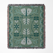 Decorative blanket with moth and floral pattern on a green background