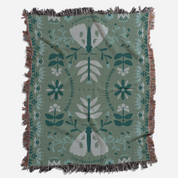 Decorative blanket with moth and floral pattern on a green background