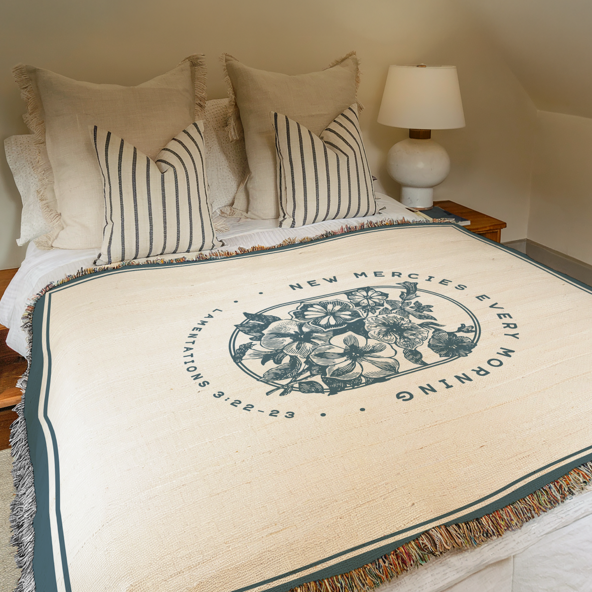 Bed with decorative blanket featuring text and floral design, lamp on nightstand.