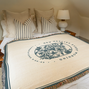 Bed with decorative blanket featuring text and floral design, lamp on nightstand.