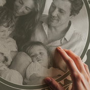 Black and white photo of a family with two children, held by a hand.
