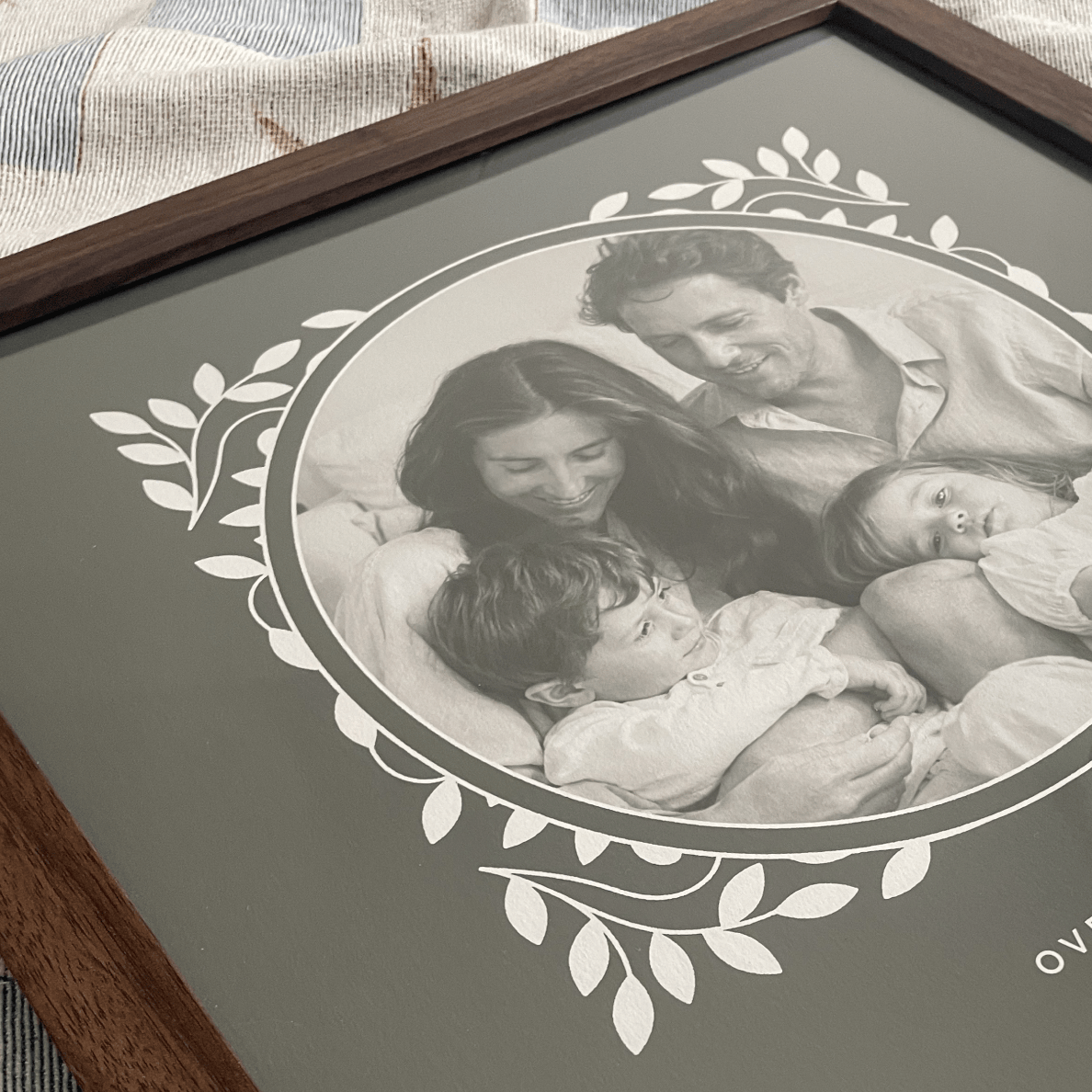 Framed black and white family photo with decorative border on a textured surface