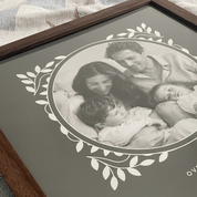 Framed black and white family photo with decorative border on a textured surface