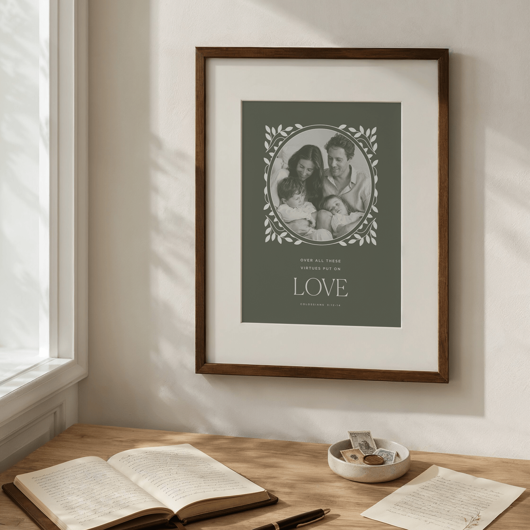 Framed family photo with 'LOVE' text on a wall above a desk with books and a bowl.