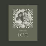 A square printed card or poster with an olive green background and a central oval photo of a family, surrounded by a white leafy border. Below the photo, the text reads 'OVER ALL THESE VIRTUES PUT ON LOVE' with 'COLOSSIANS 2:12-14' underneath.