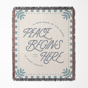 Blanket with 'Peace Begins Here' text and decorative patterns on a white background