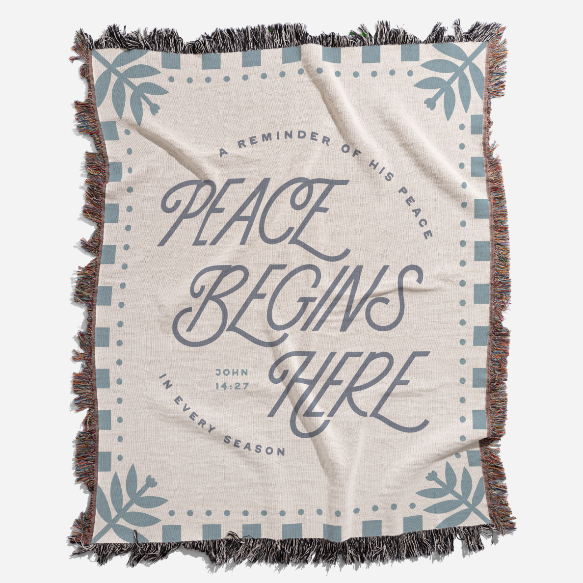 Blanket with 'Peace Begins Here' text and decorative elements on a white background