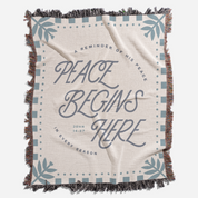 Blanket with 'Peace Begins Here' text and decorative elements on a white background