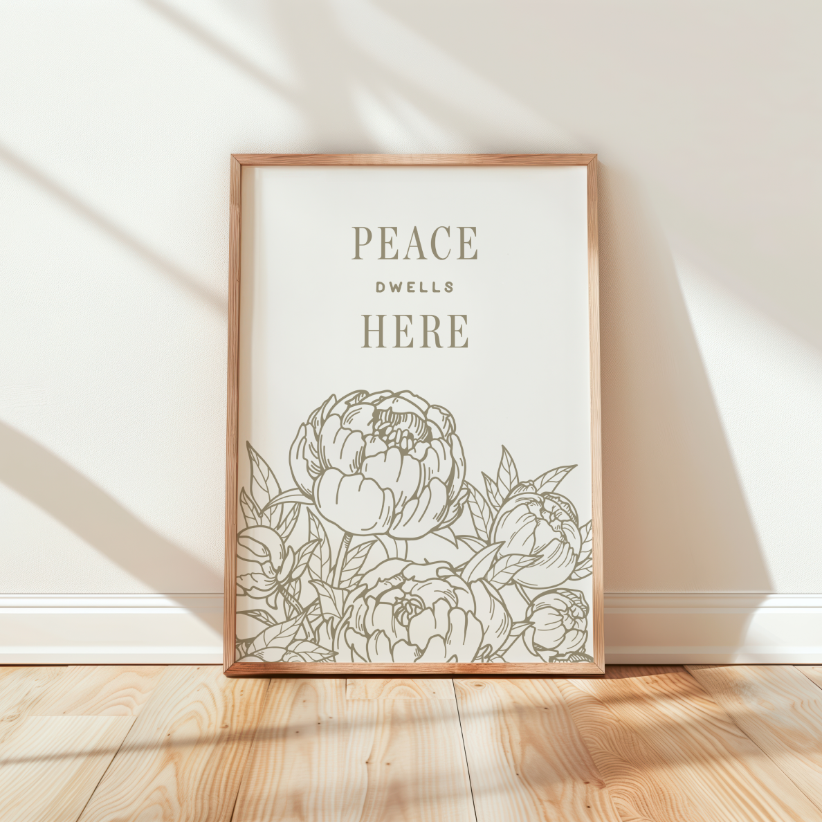 Framed artwork with floral design and 'Peace Dwells Here' text on a wall.