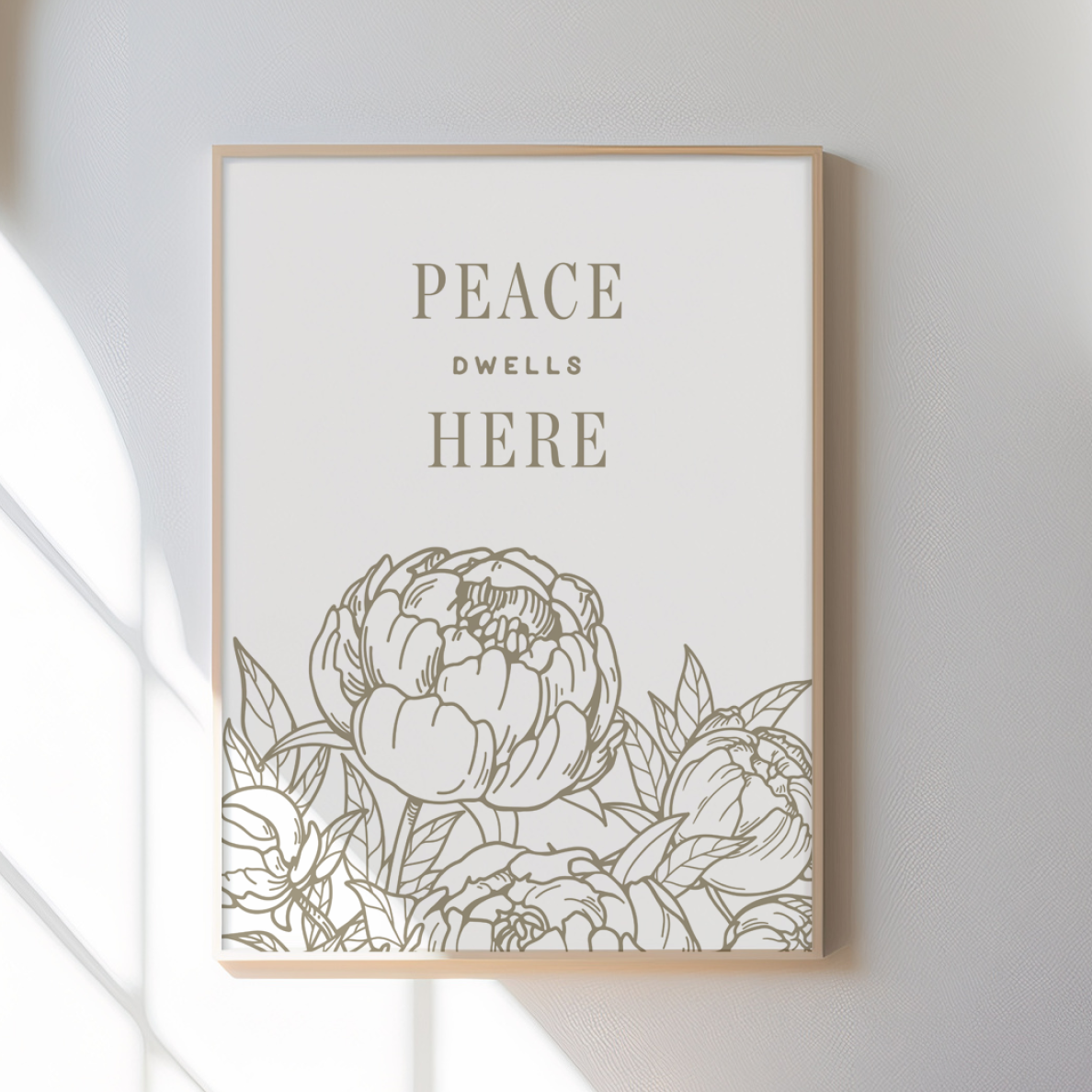 Framed artwork with floral design and 'Peace Dwells Here' text on a white wall.
