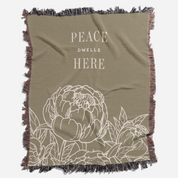 Olive green blanket with floral design and 'Peace Dwell Here' text on a white background