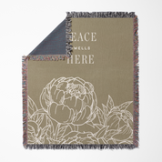 Blanket with floral design and 'Peace Wells Here' text on a beige background