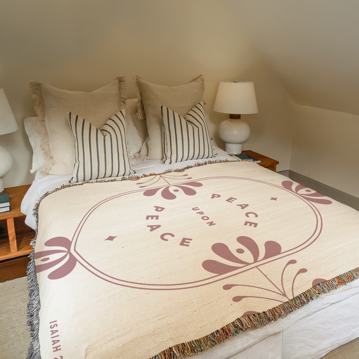 Bed with decorative blanket featuring 'Peace Upon Peace' text and floral design, in a cozy bedroom setting.