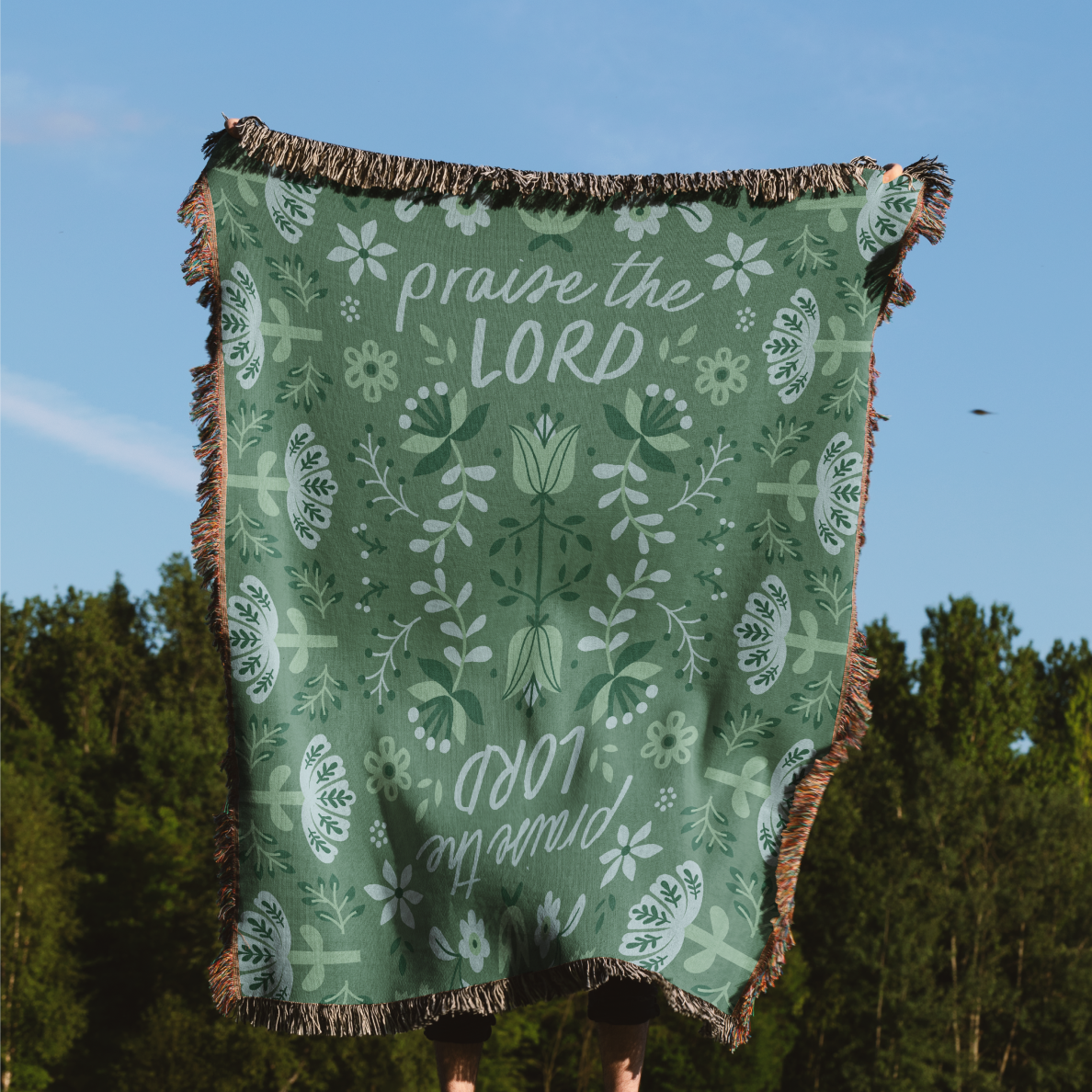 Green blanket with 'praise the LORD' text and floral patterns against a forest background