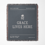 Gray throw blanket with text and a flower design on a white background