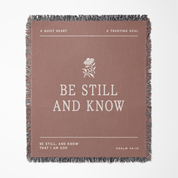 Brown blanket with 'Be Still and Know' text and design on a white background