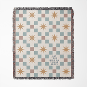 Woven blanket with star pattern and motivational quote on a white background