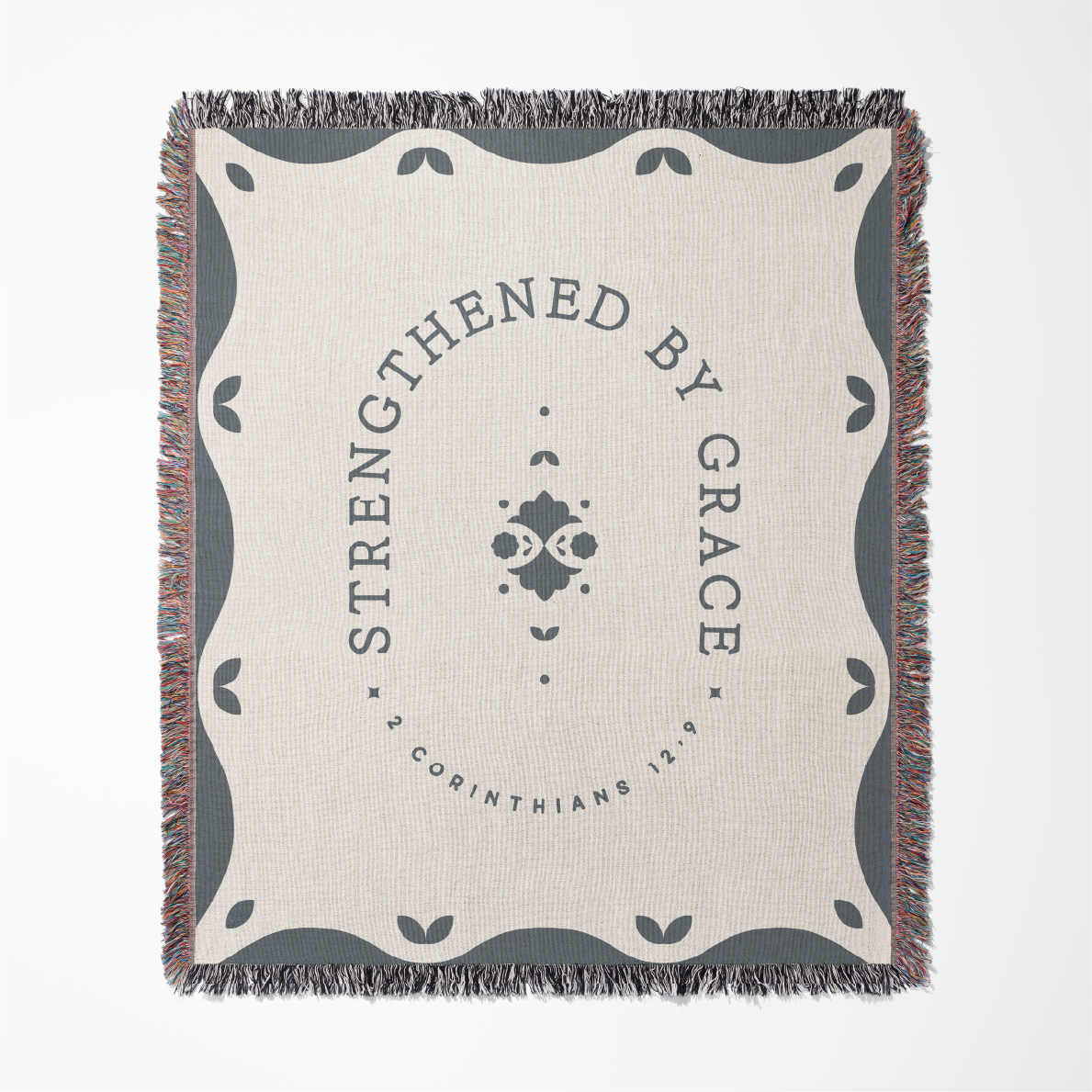 Blanket with 'Strengthened by Grace' text and decorative border on a white background