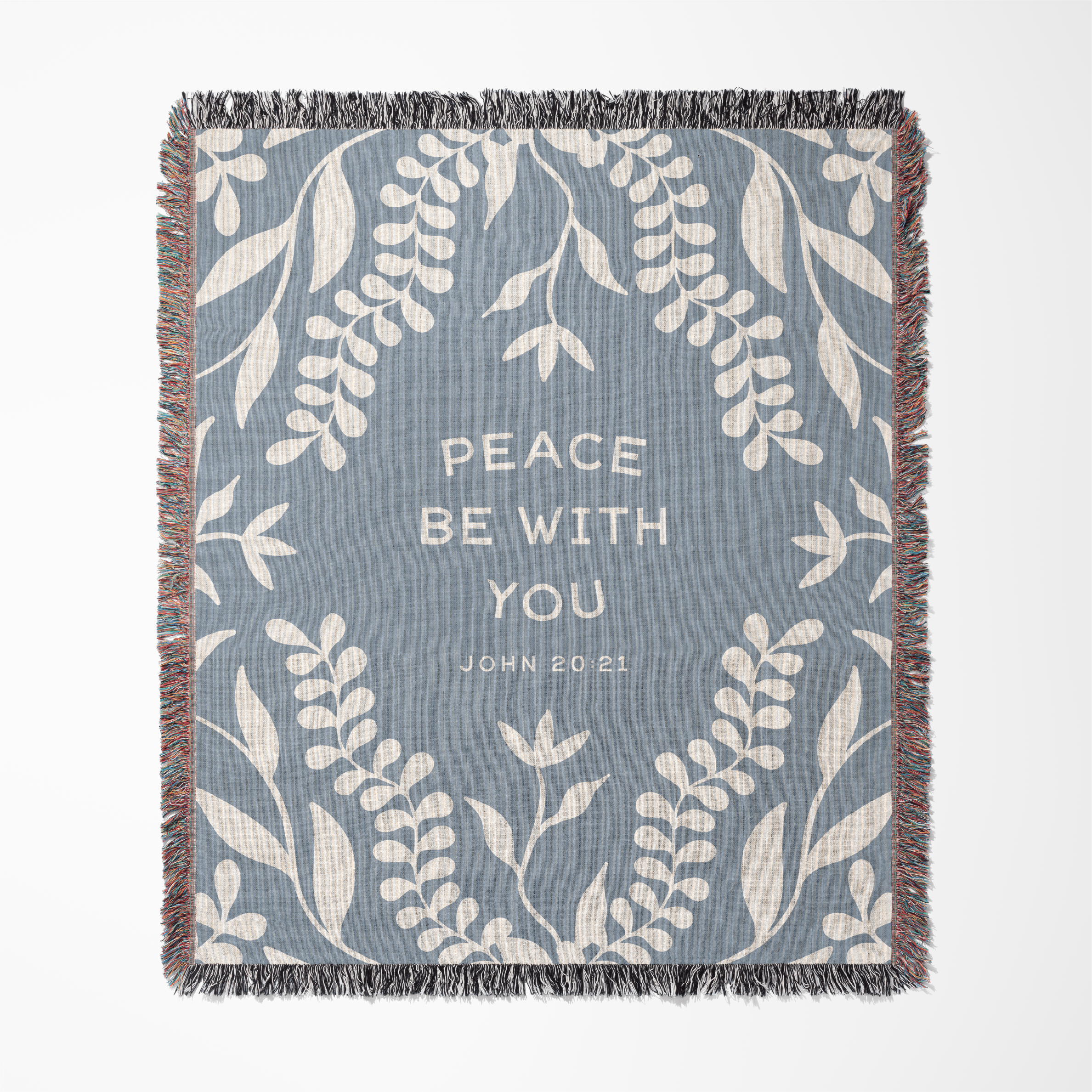 Woven blanket with leaf pattern and 'Peace be with you' text on a blue background