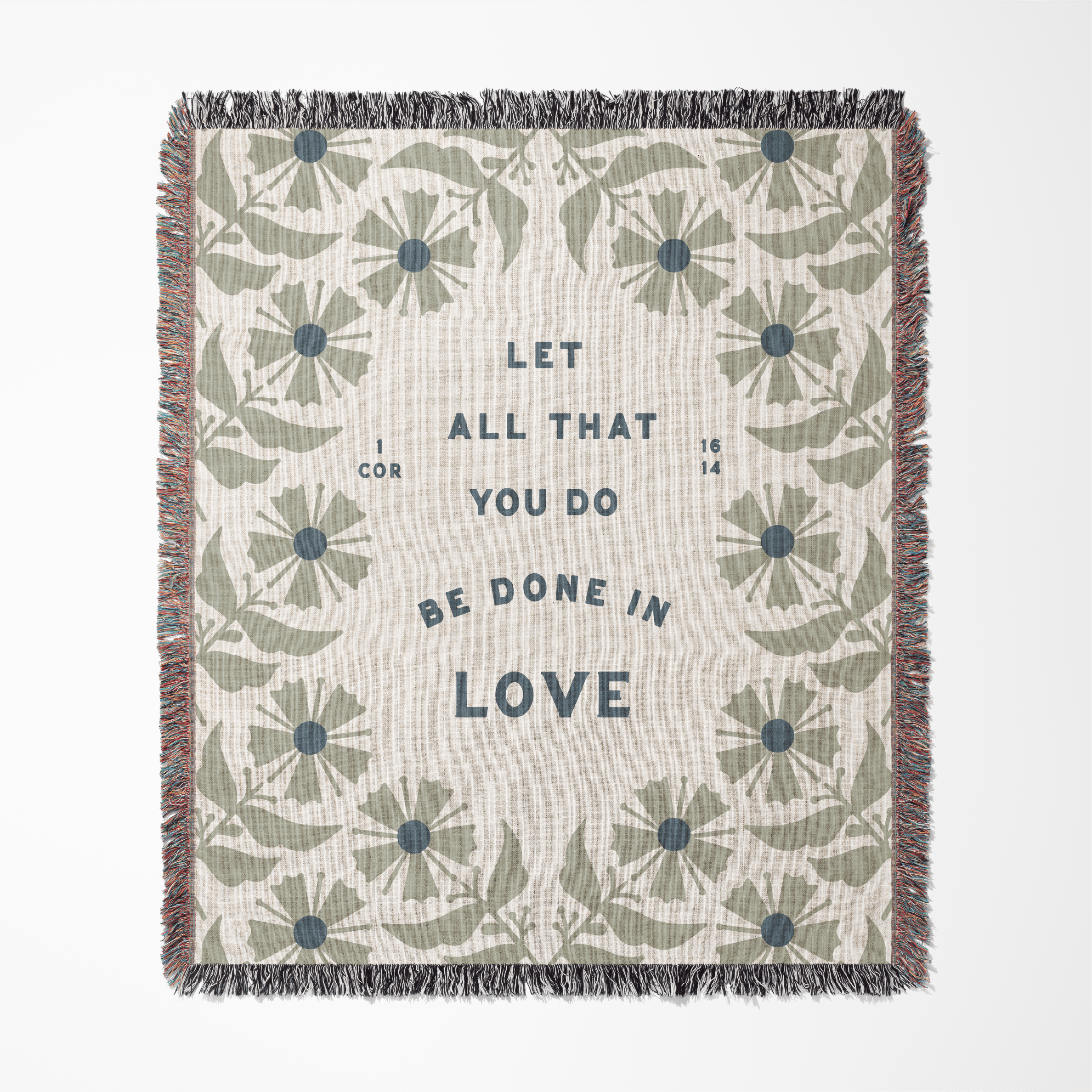 Floral patterned blanket with text 'Let all that you do be done in love' on a white background
