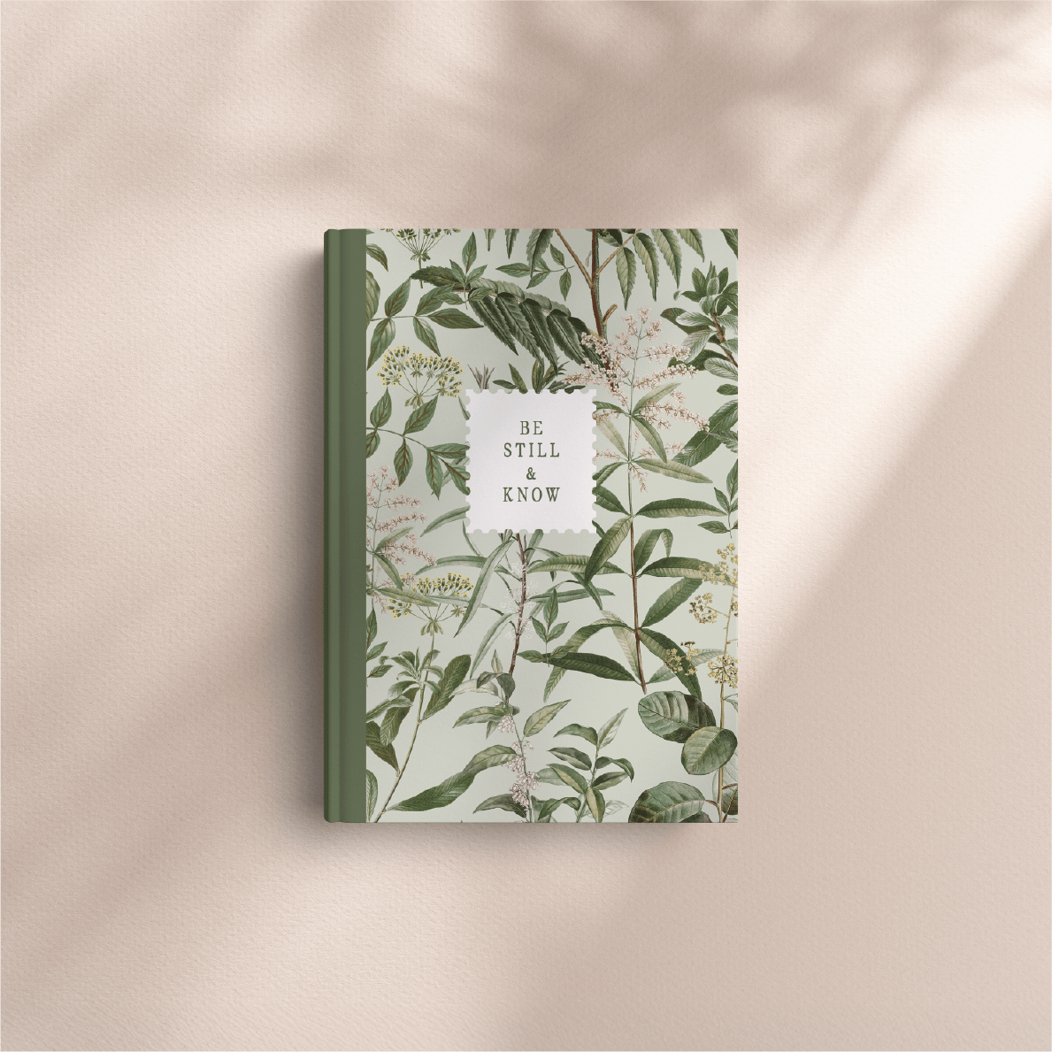 Notebook with botanical design and 'Be Still and Know' text on a beige background