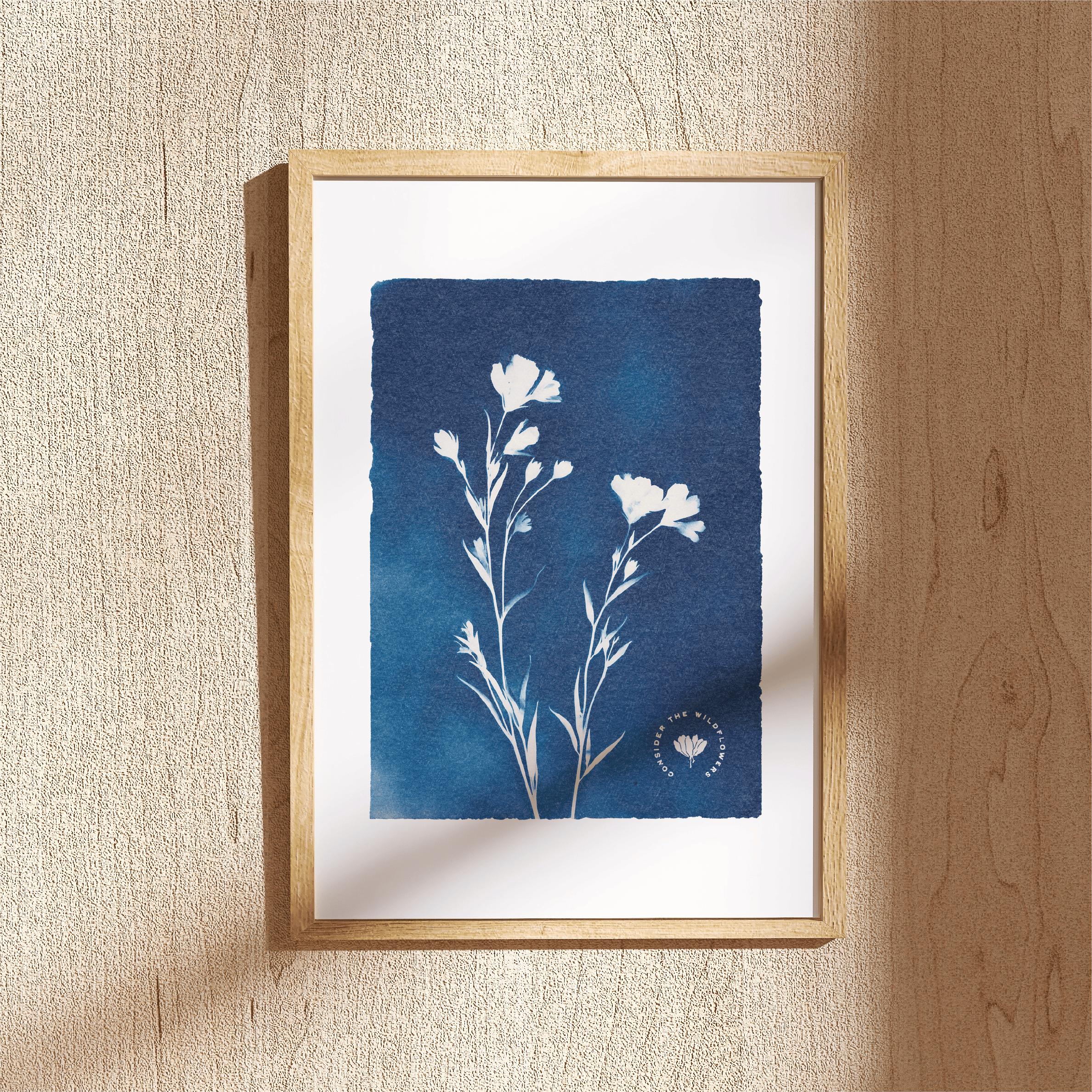 Framed botanical print with blue floral design on a beige wall.